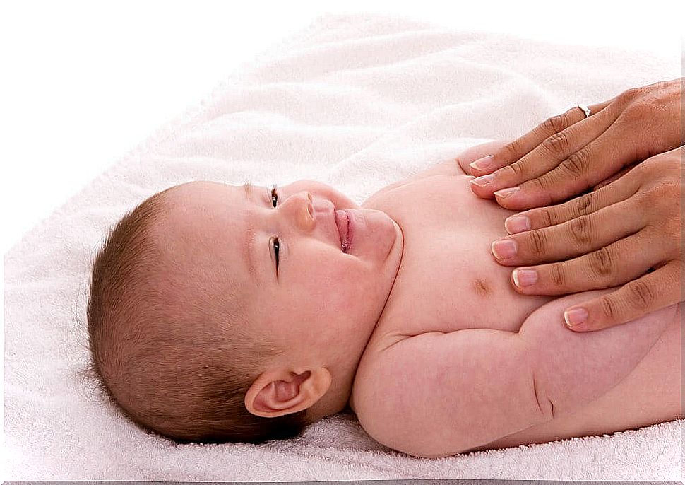 Smiling baby being massaged by the hands of an adult, a relaxation exercise for children