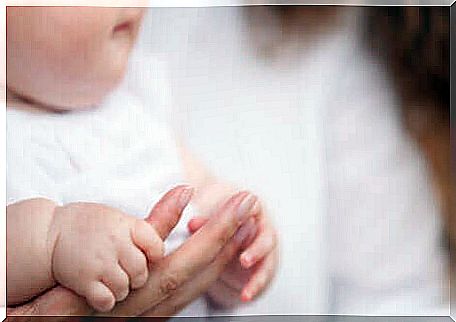 A baby holding his mother's hand.