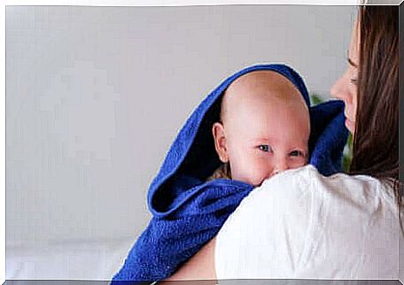 A baby coming out of the bath in a towel.