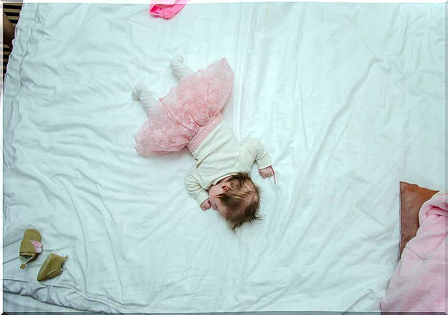 A little girl asleep in a big bed 