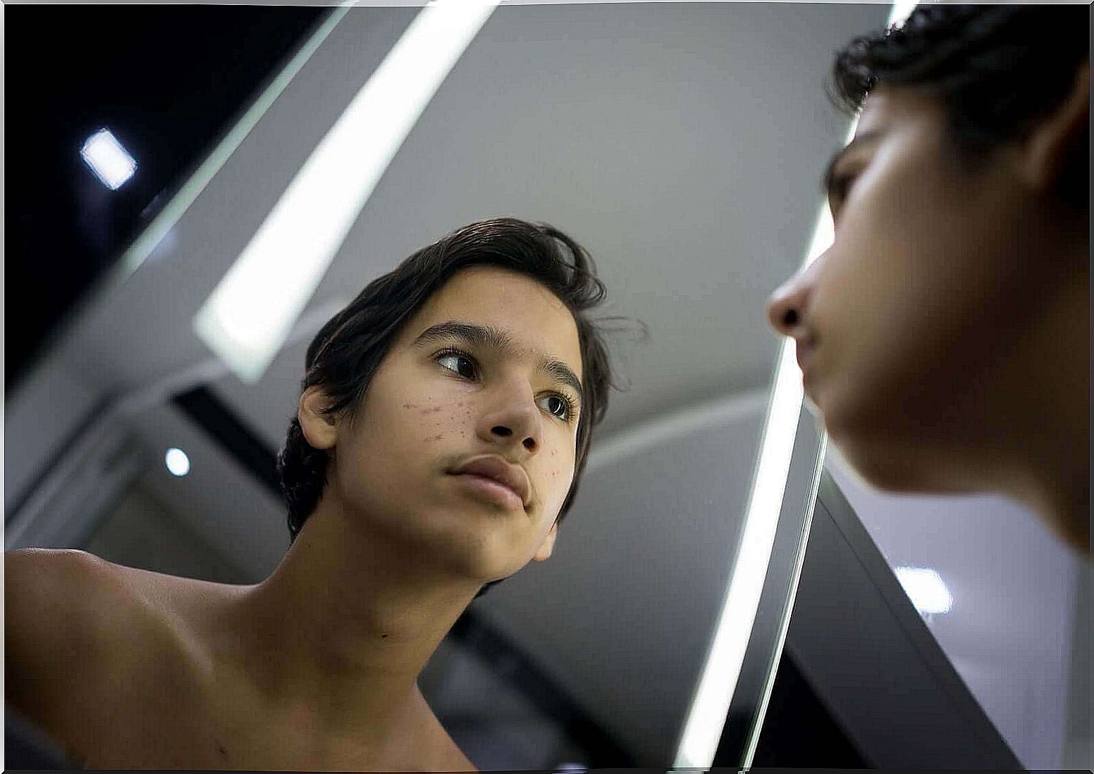 A teenager looking at himself in the mirror.