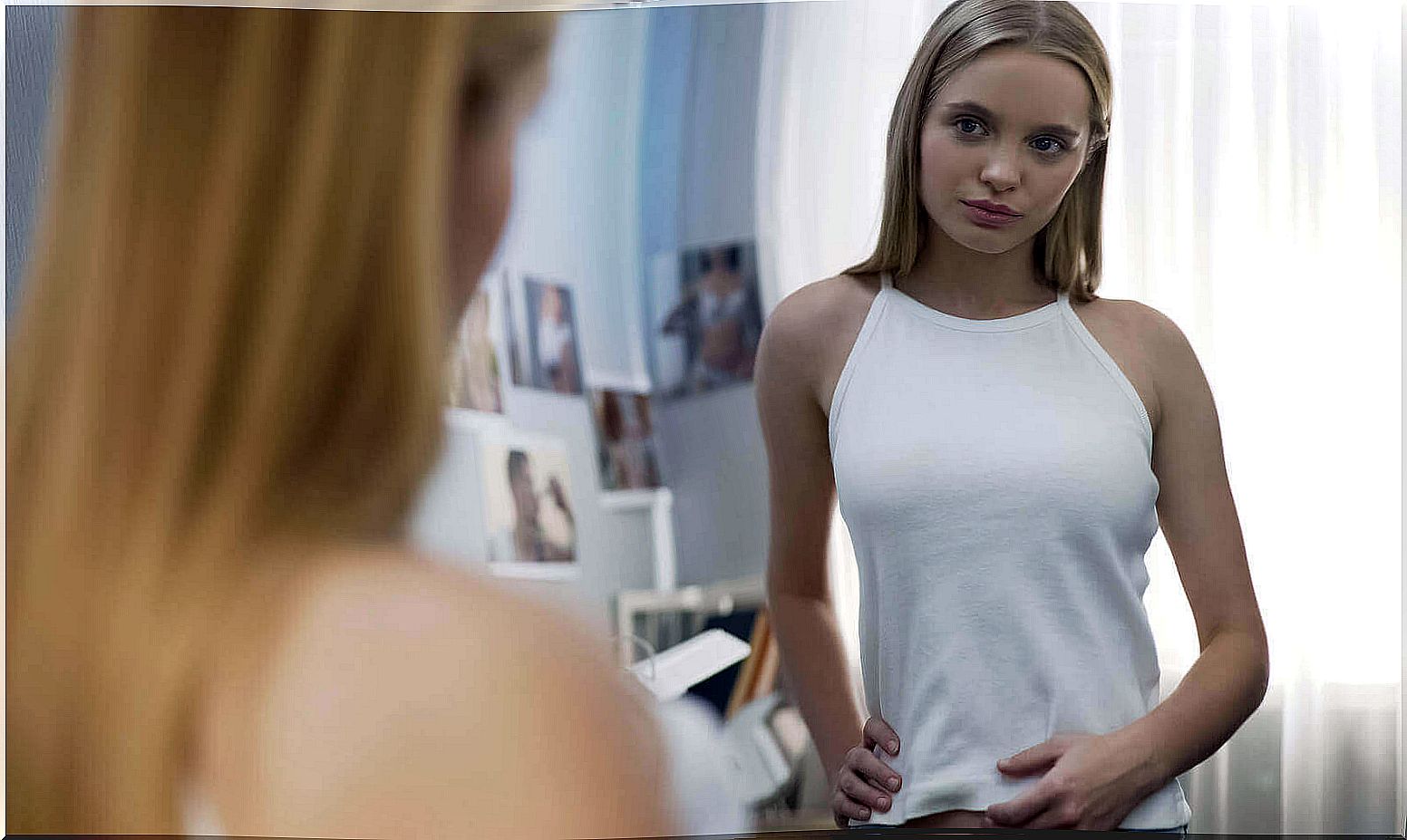 A teenage girl looking at herself in a mirror.