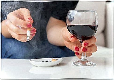 A woman drinking a glass of wine and smoking