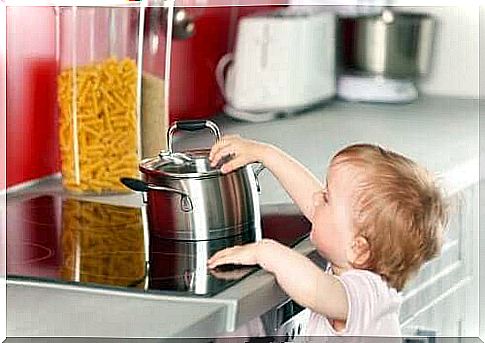 A child touching a pan on the hotplates. 