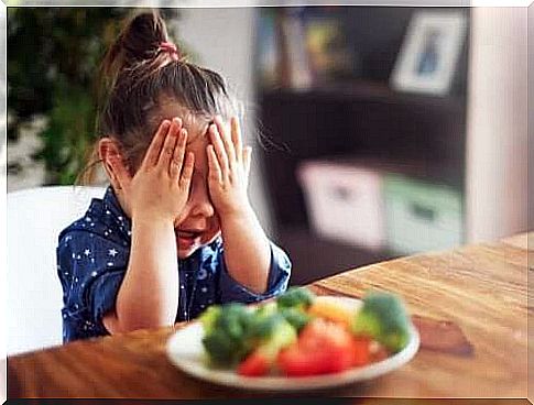 A child hiding her eyes in front of vegetables