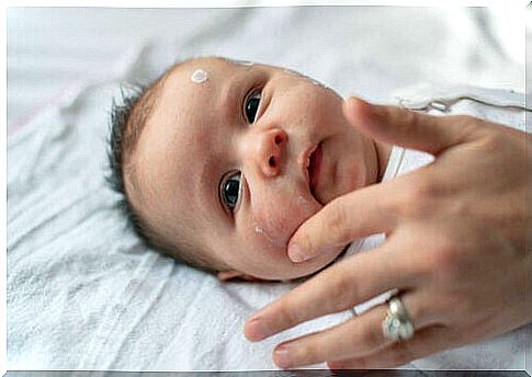 A mom puts cream on her baby's face to moisturize it.