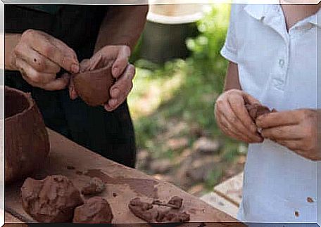 An adult and a child playing with clay. 