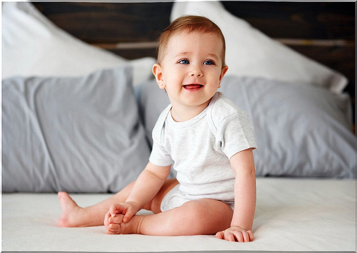 A baby sitting in a big bed. 