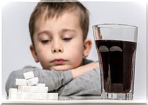 A child in front of a glass of soda and its sugar equivalent