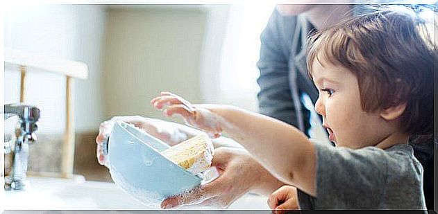 Child doing the dishes with his mom