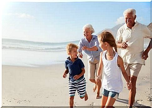 grandparents running on the beach with their grandchildren