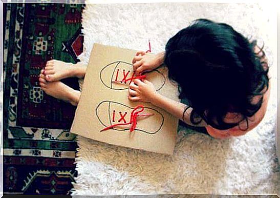 A little girl ties and unties shoe laces on a cardboard game