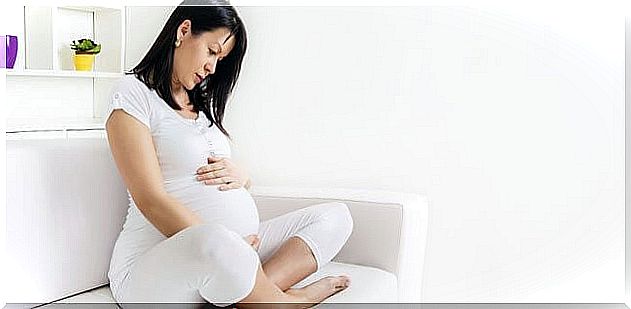 Pensive woman in full pregnancy sitting on a sofa