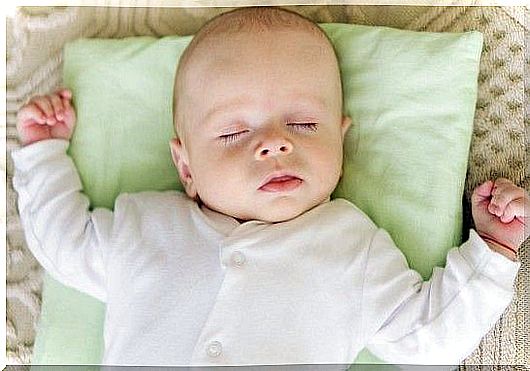 A newborn baby asleep on his back on a pillow although pillows for babies should be avoided